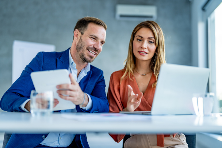 male and female at a desk looking at computer screen