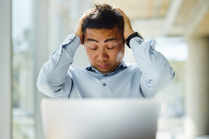 Worried businessman working on laptop in an office setting